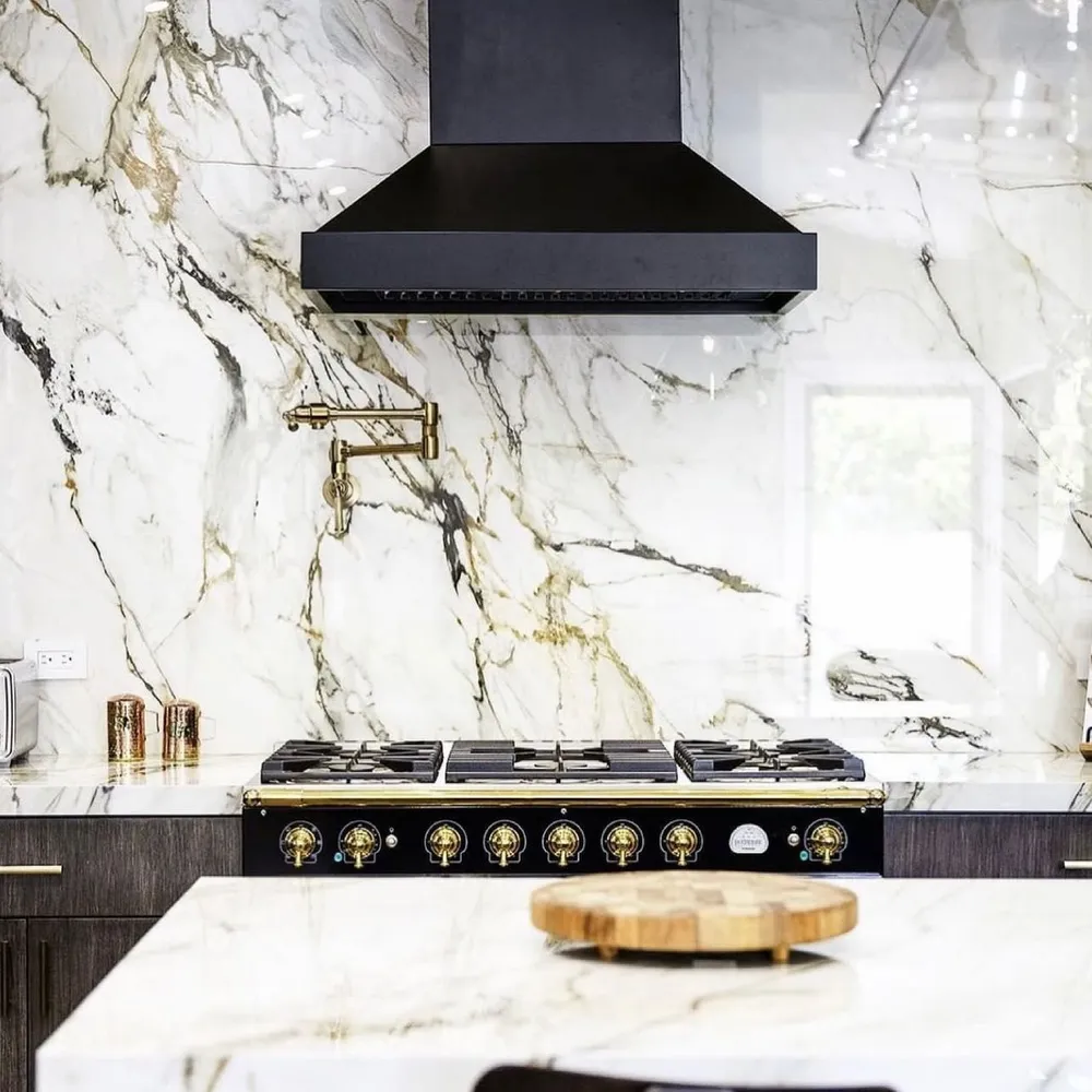 Kitchen with a full-height marble stone backsplash wall and gold-accented range