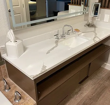 Custom stone vanity top with white veined surface and wood cabinetry