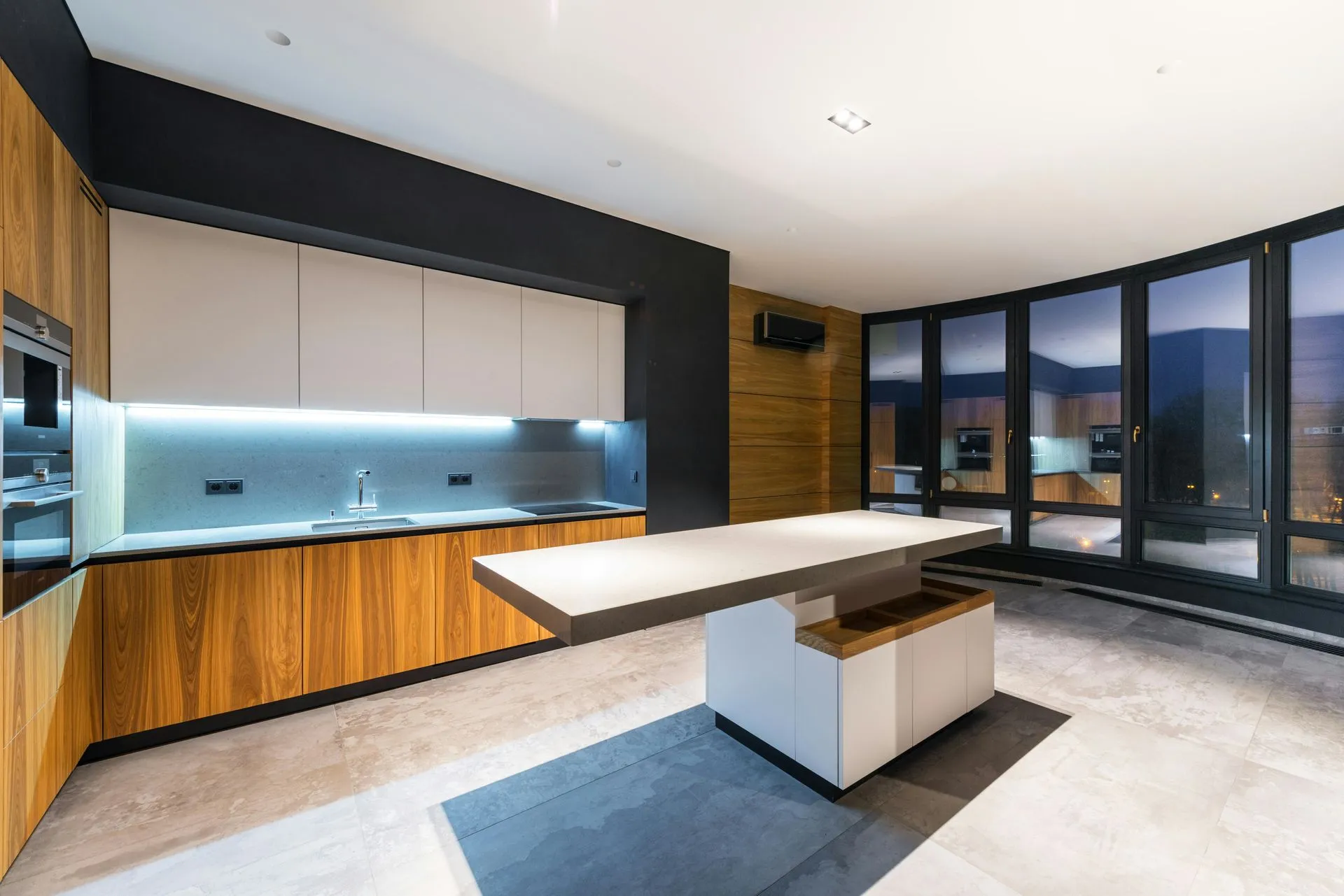 Modern Las Vegas kitchen with a floating stone island, wood cabinetry, and floor-to-ceiling windows at dusk